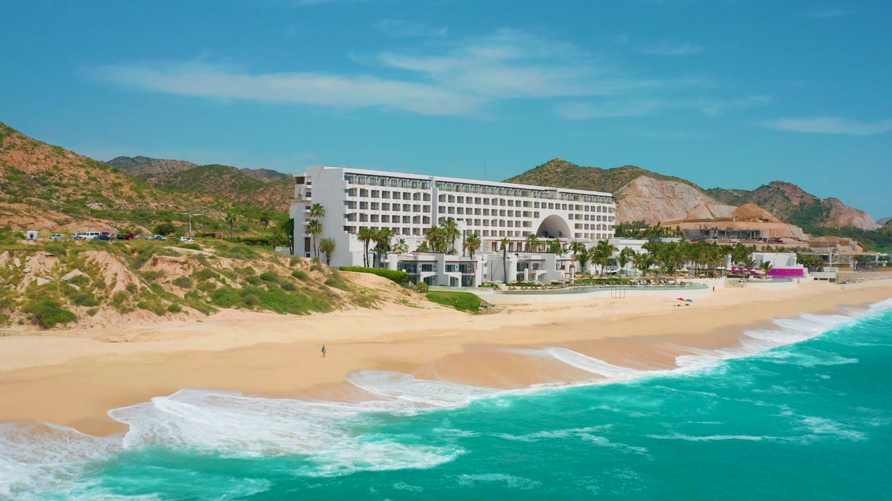 White resort above a sandy beach with turquoise surf