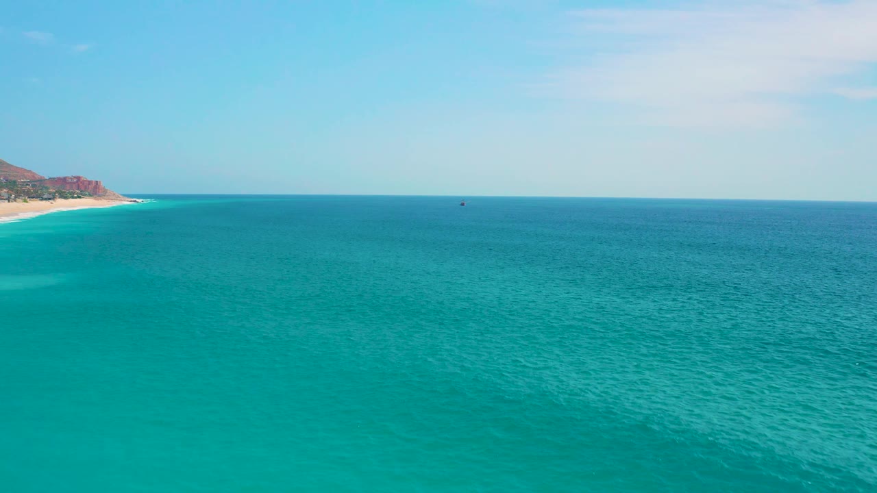 Blue-green ocean surface stretches to a straight horizon near Secrets Marquis Los Cabos, Mexico, with the far coastline held at the left and no visible people.