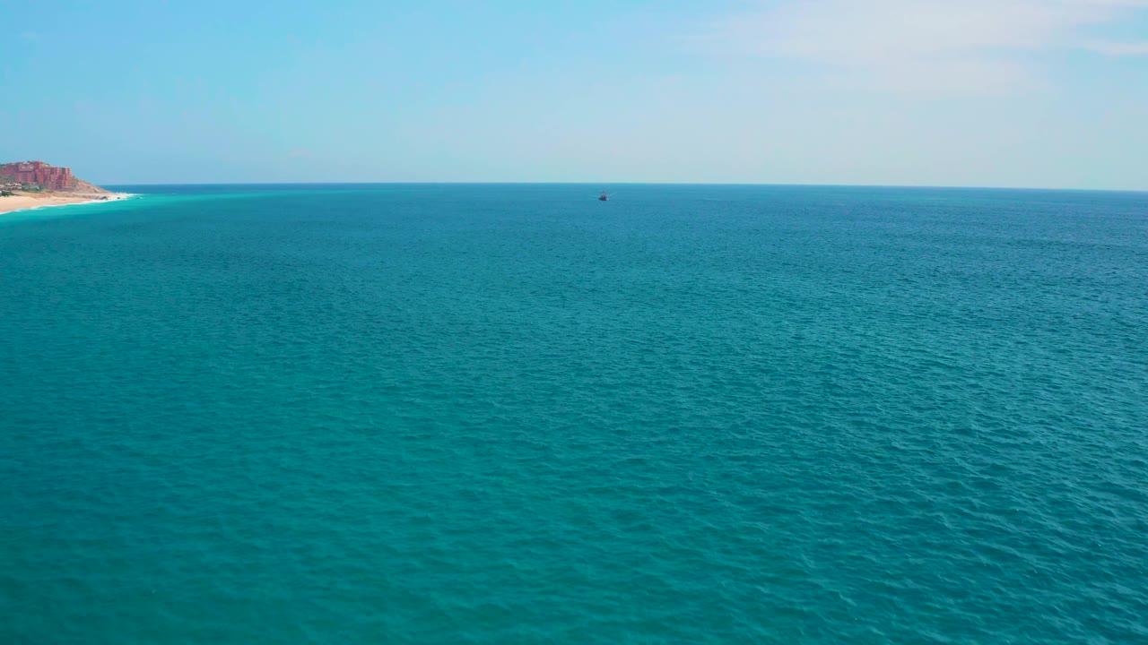 Open blue-green sea fills the frame near Secrets Marquis Los Cabos, Mexico, with the rocky shoreline still visible on the far left and no visible people.