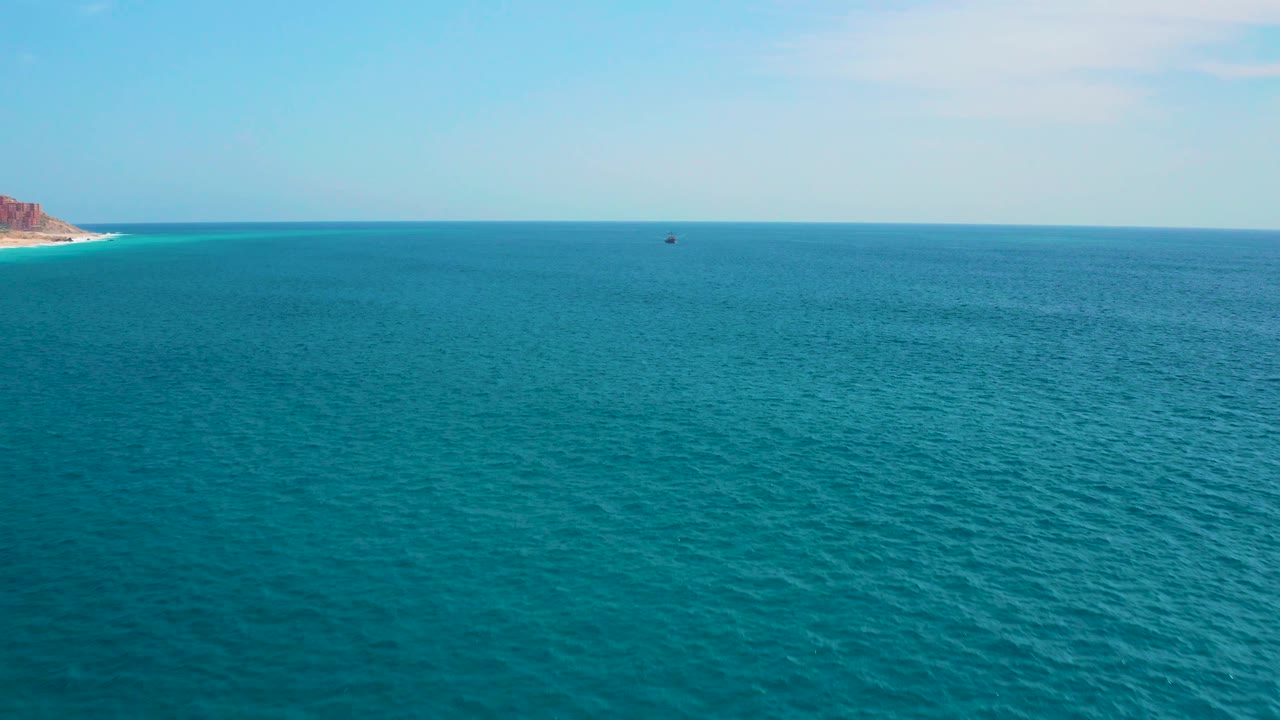 Fourth frame shows empty-looking blue-green water in Los Cabos, a thin pale sky above the horizon, a small offshore speck, and no visible people.