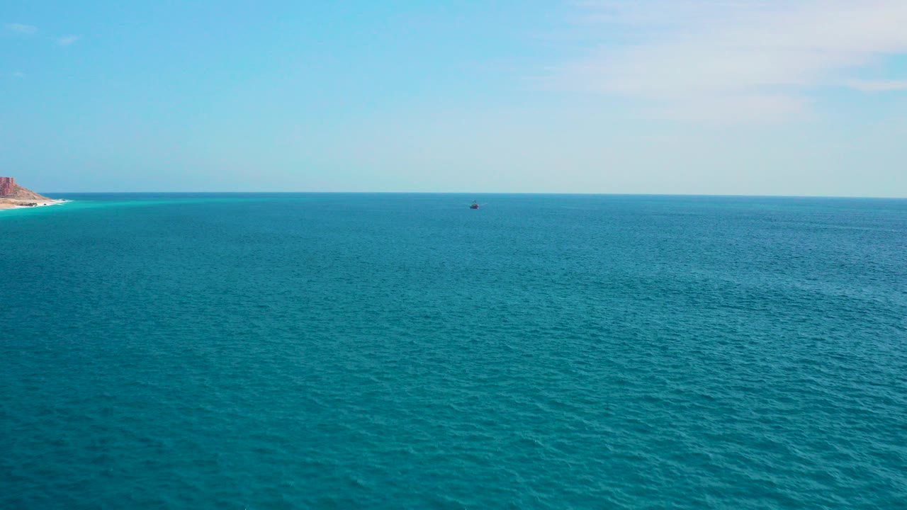 Wide turquoise ocean with a pale sky and distant horizon.