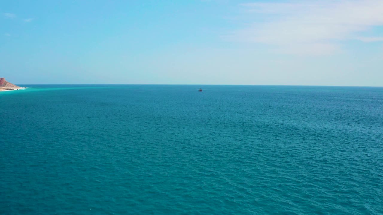 Third frame holds a wide turquoise sea near Secrets Marquis Los Cabos, Mexico, with faint clouds above, a sliver of rocky coast on the far left, a tiny vessel near the horizon, and no visible people.