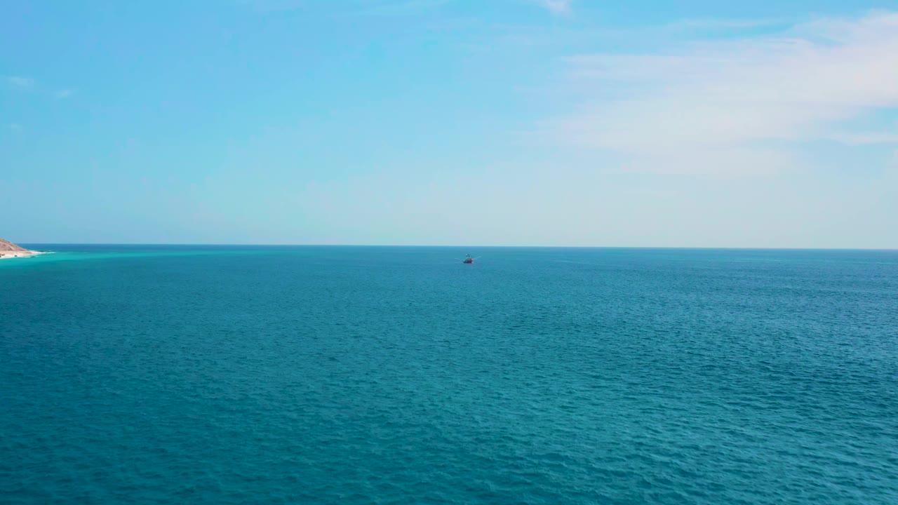 At 0:01, the frame holds on blue water, a straight horizon, a soft white cloud high to the right, a tiny boat near the distant center, and no visible people.