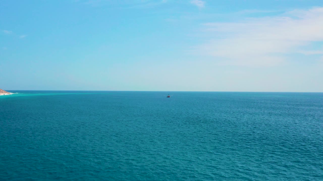 At 0:02, the Secrets Marquis Los Cabos, Mexico view shows textured blue water, a clear sky, the small boat slightly right of center, and no visible people.
