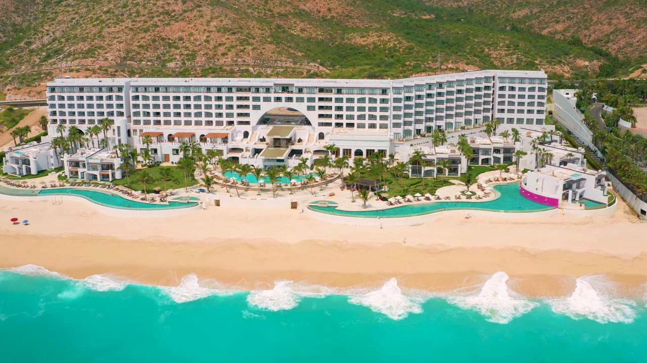 Beachfront resort seen from above with ocean waves along the lower edge.