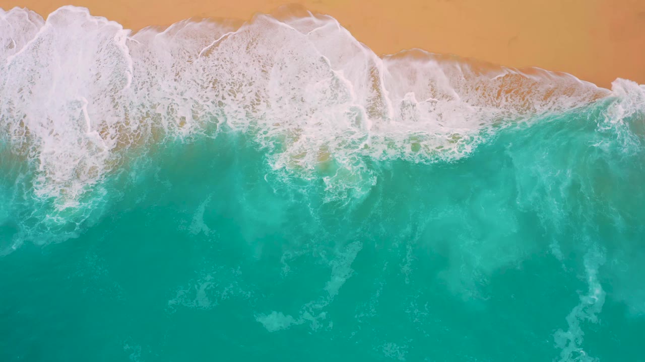 White foam spreading across a turquoise shoreline