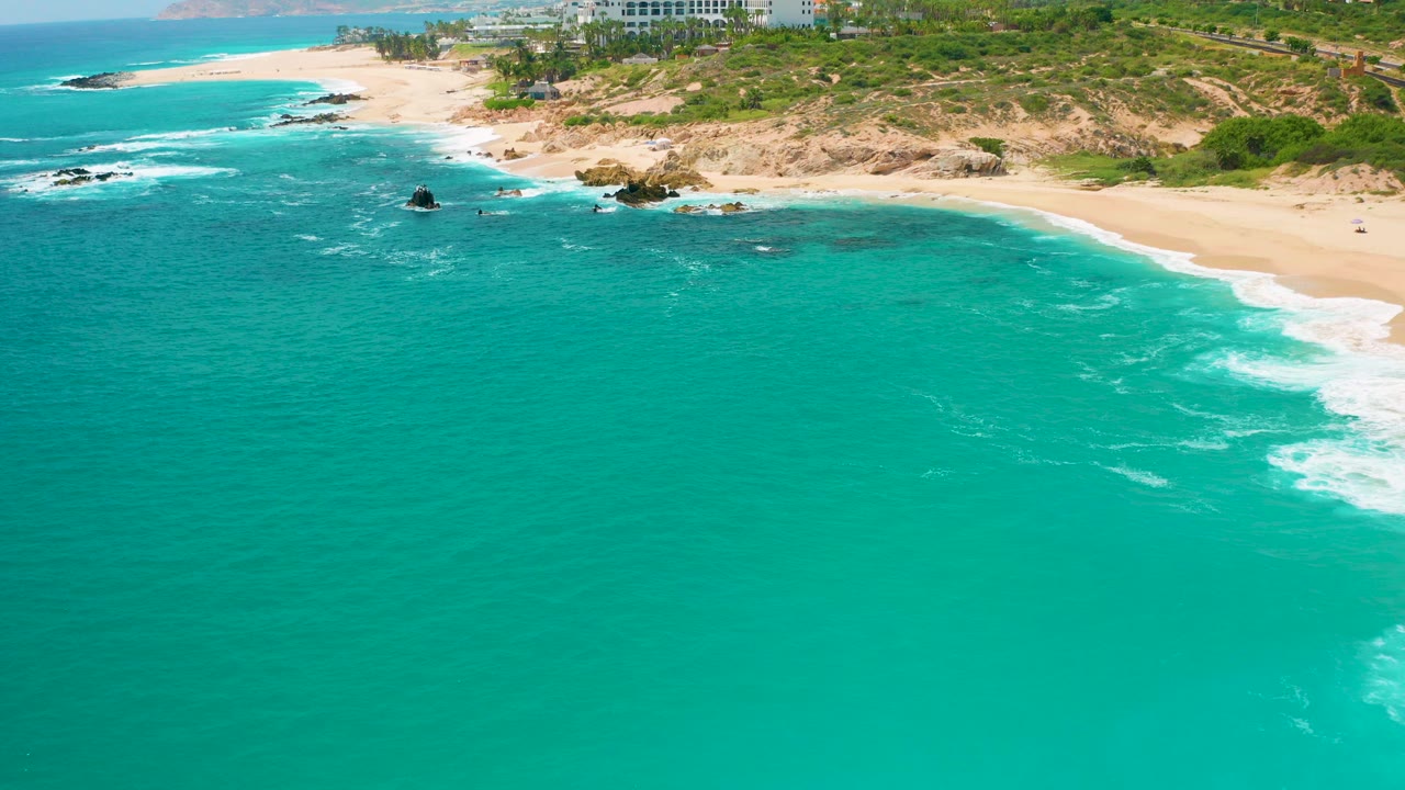 Aerial view of turquoise ocean beside a sandy coastline.