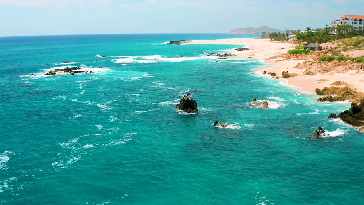 Aerial beach view with central rock and foamy water trails