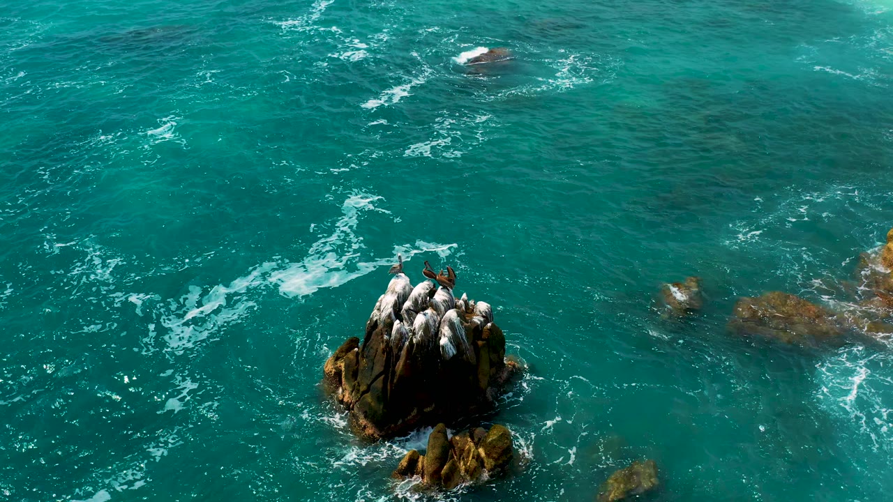 Rocky outcrop below an overhead view of blue-green water.