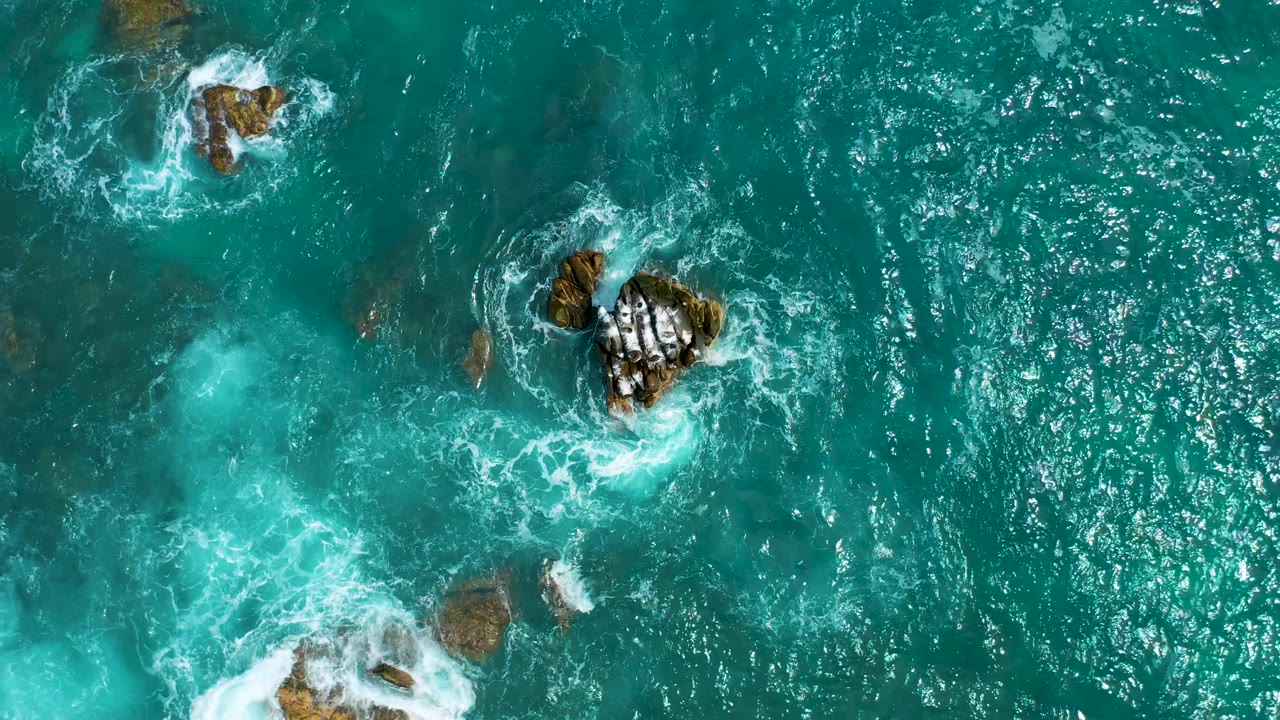 Bright blue water around a central rock cluster