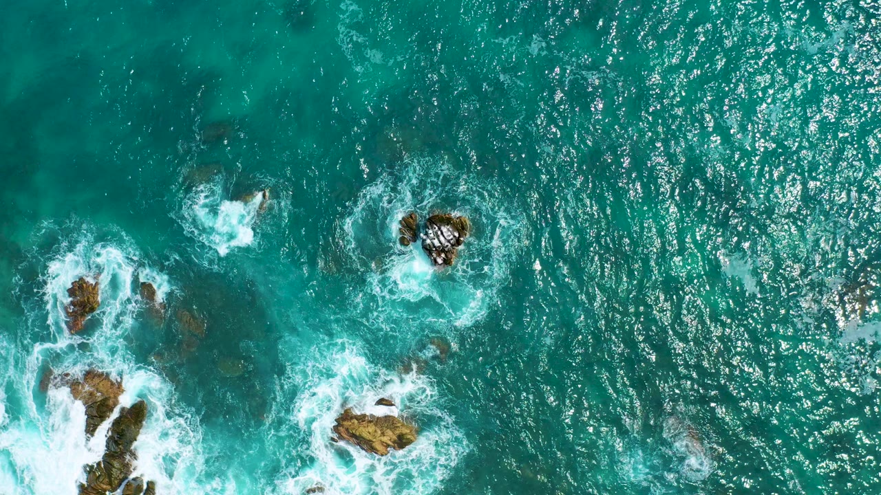 Turquoise ocean with white surf around small rocks
