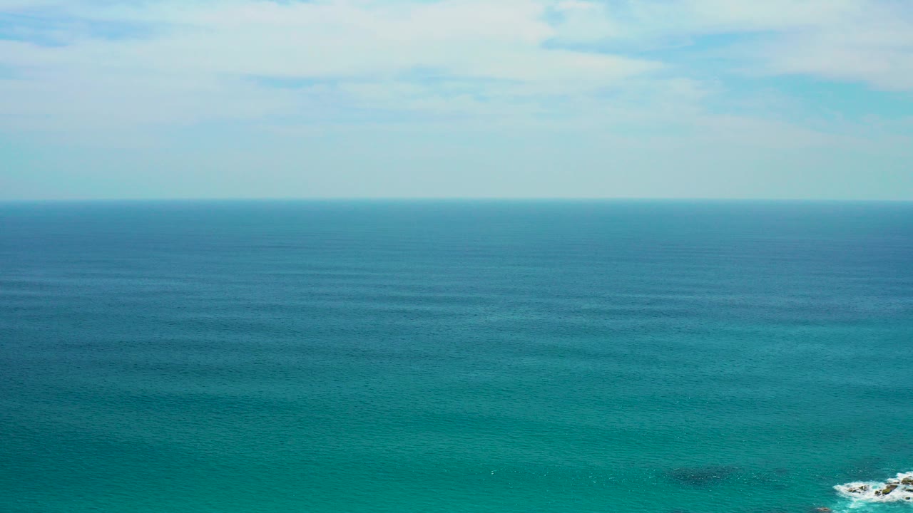 Wide aerial view over blue-green ocean at Secrets Marquis Los Cabos, Mexico, with a pale sky, distant horizon, and no visible people.