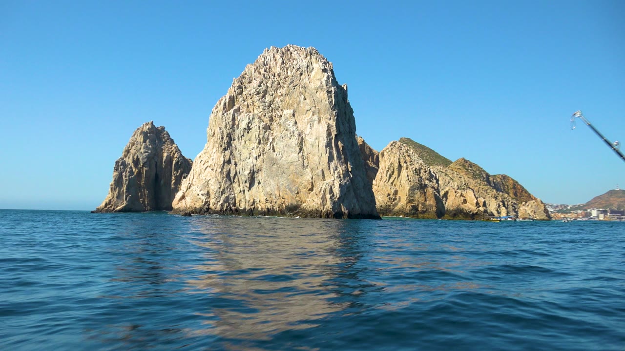 Cabo San Lucas rock formations fill the midground over blue water, while a small blurred object appears high against the sky and no visible people are present.