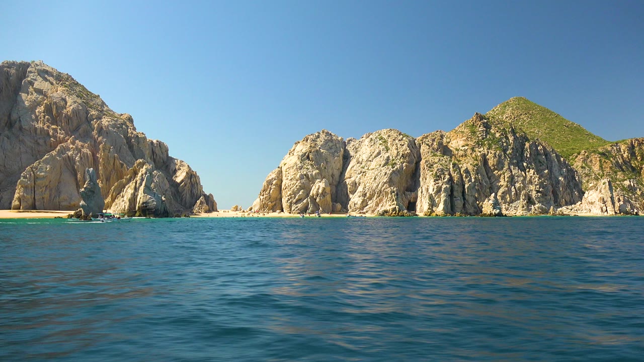 Sunlit cliffs and green hill beyond rippled ocean