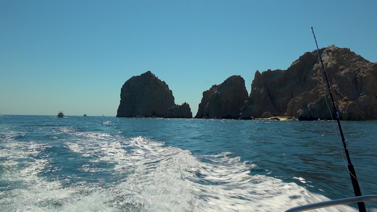 Ocean wake with rock formations and fishing rod at right