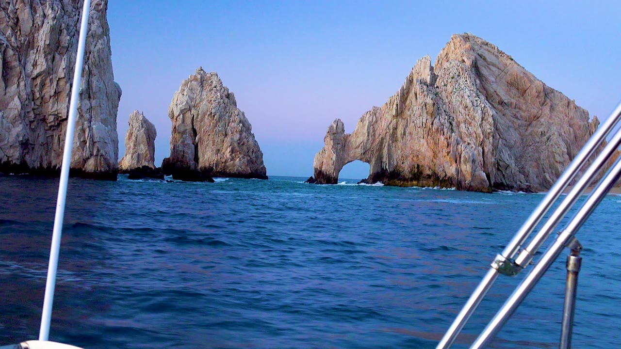 Ocean and rocky arch with boat railings in foreground