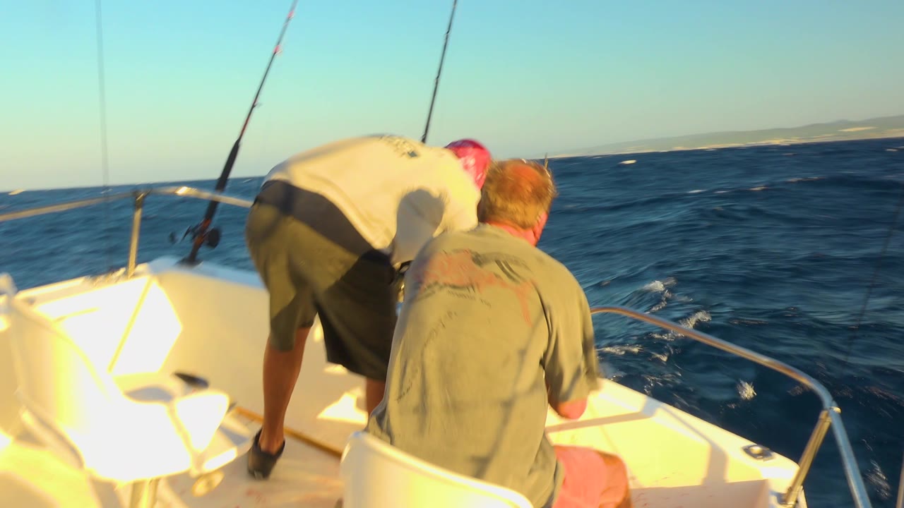 Two men remain near the bow as fishing rods face the open water.