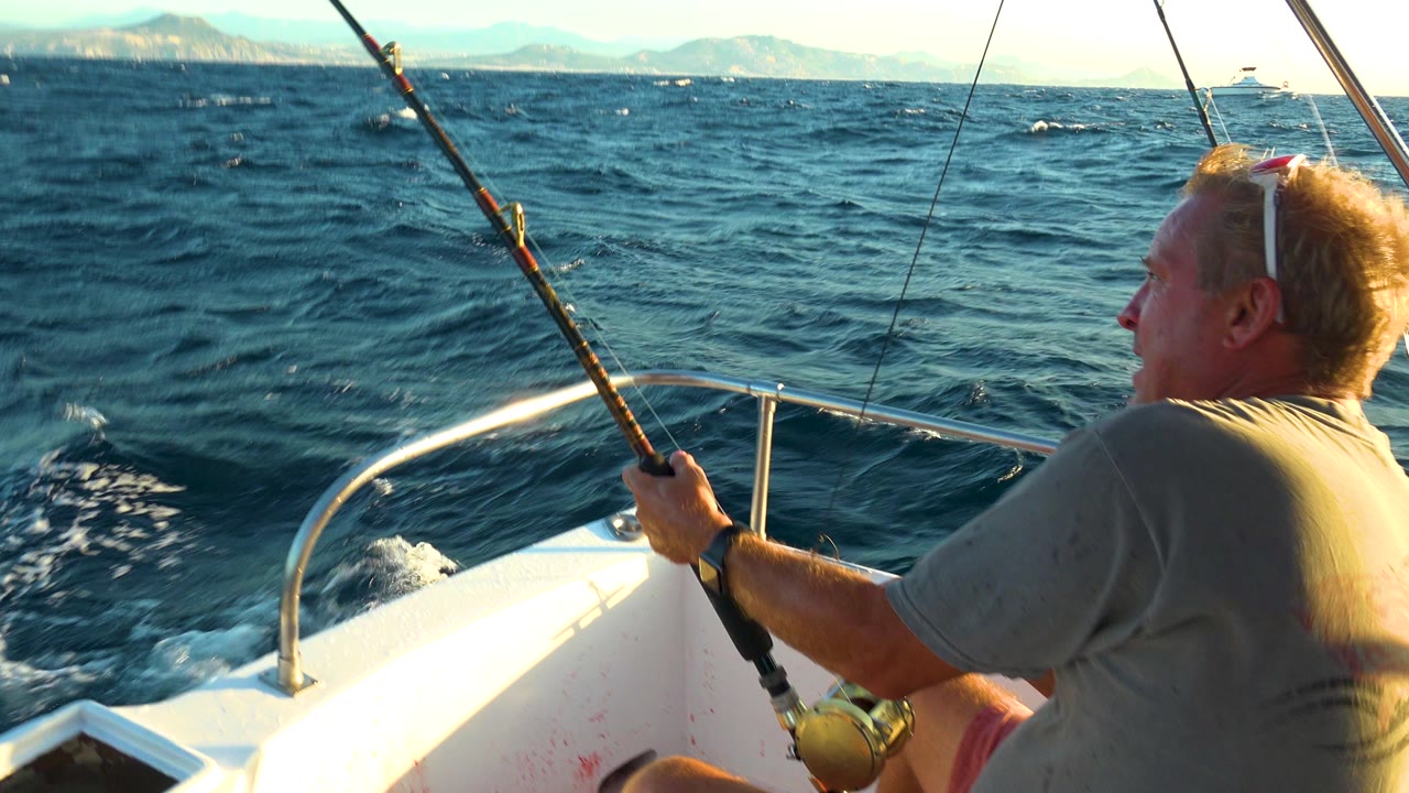 Fisherman pulls on a rod from a small boat with waves ahead.