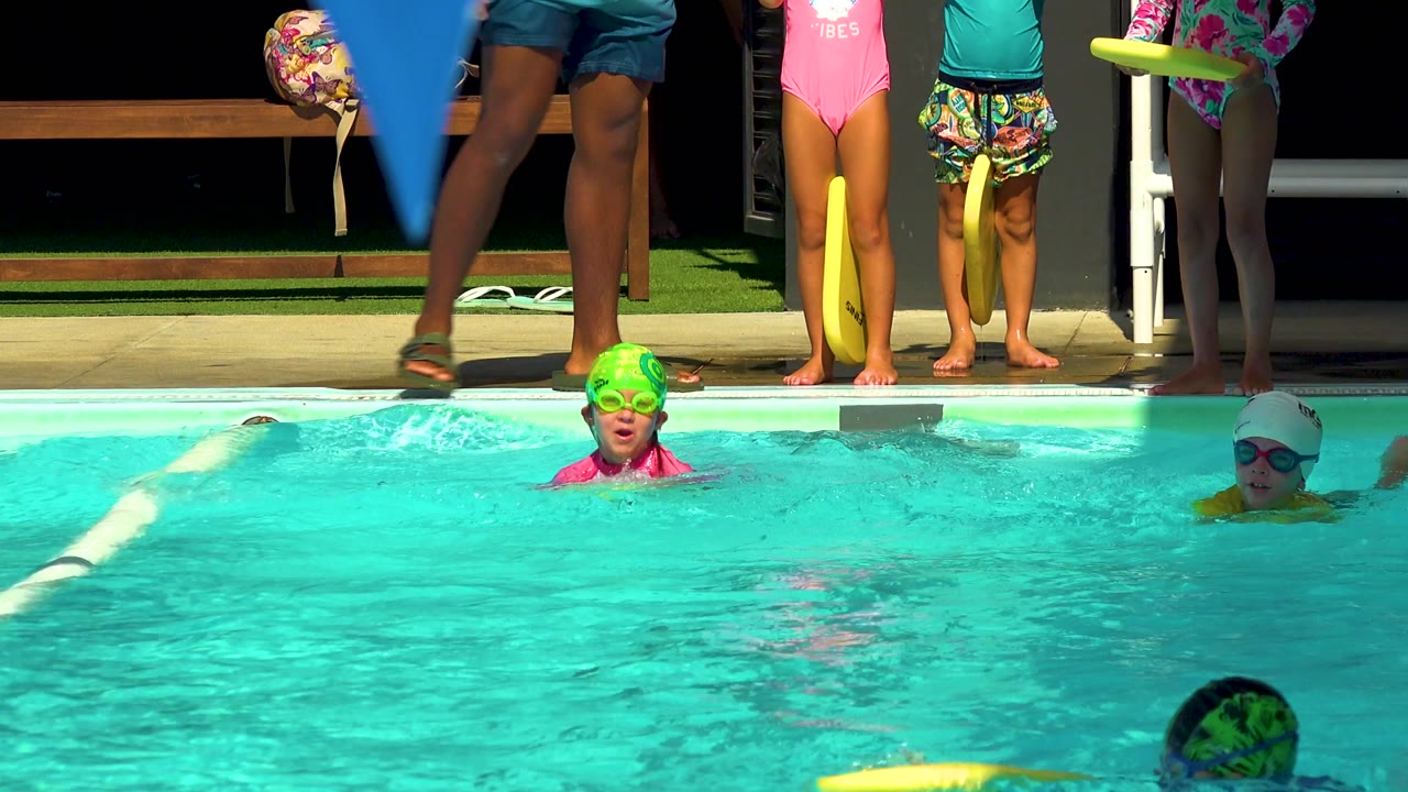 Child in green swim cap faces forward during a pool lesson.