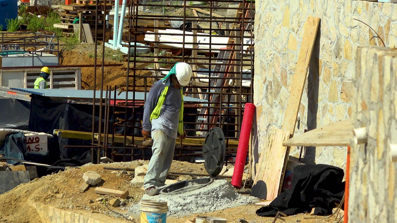 Worker walking across gravel near rebar and scaffolding.