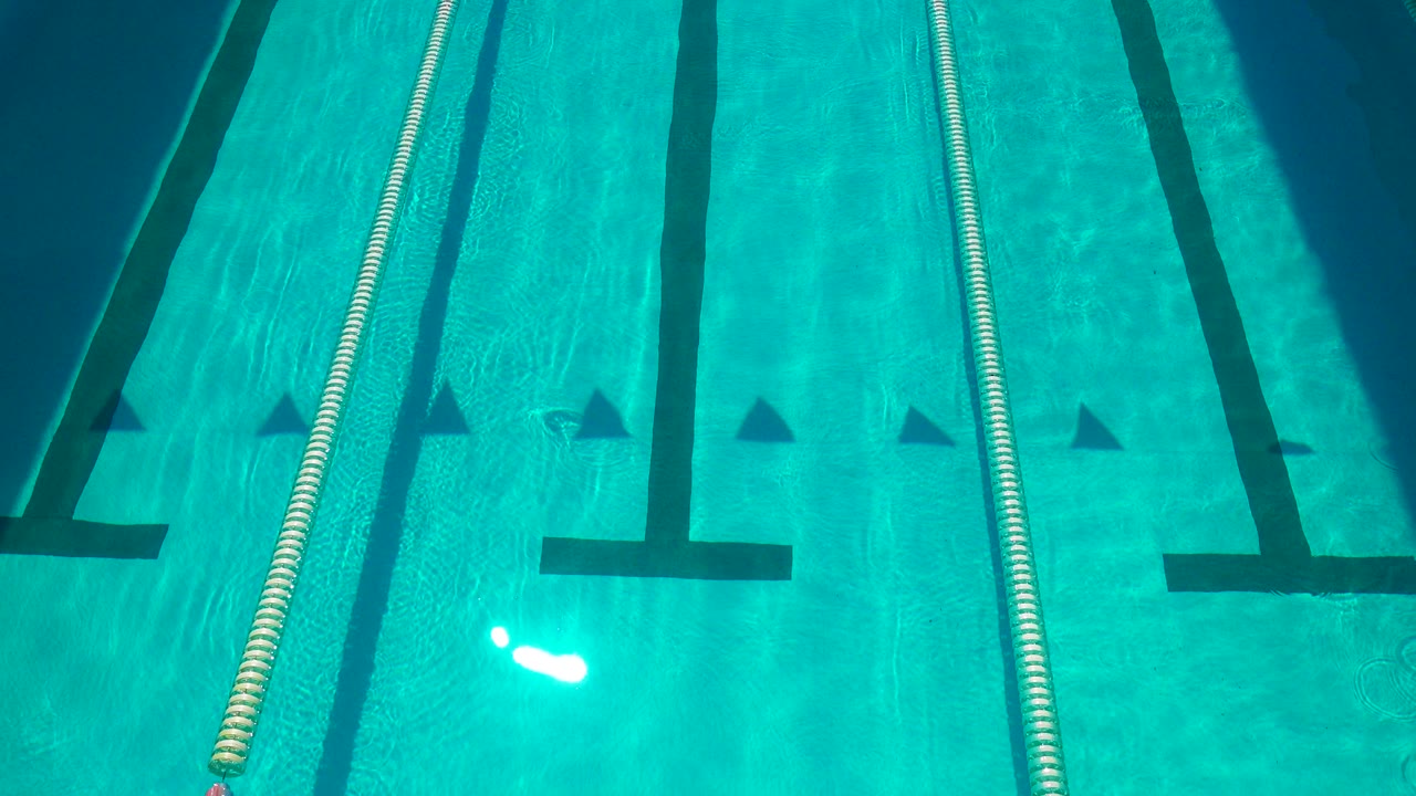 Blue competition pool lanes with lane rope and black floor markings.
