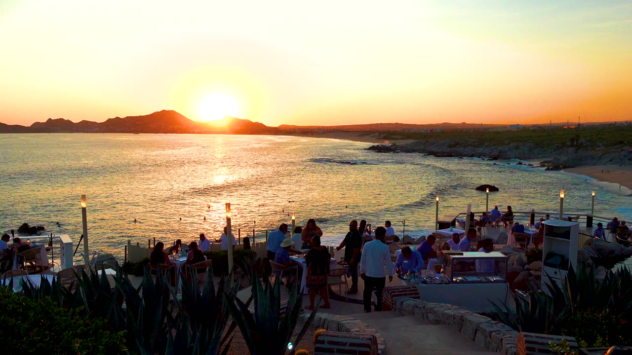 Outdoor tables and guests overlooking sunset water