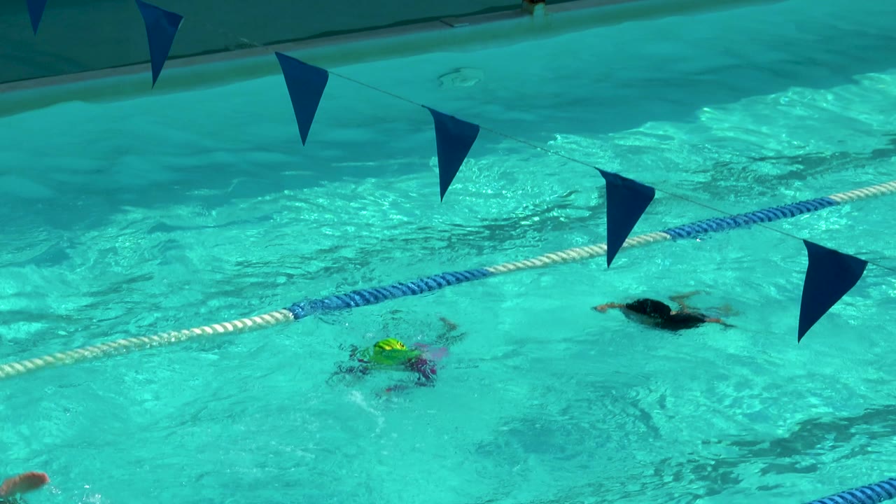 Swimmers continue through blue and white pool lanes.