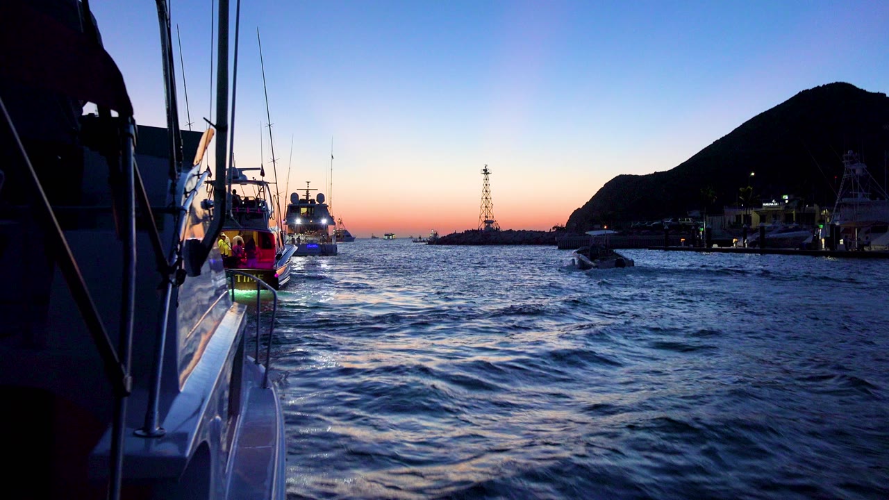 Yachts ahead on blue water with hillside at dusk