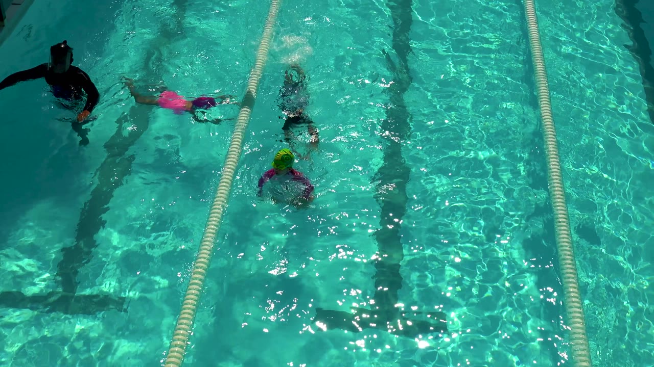Adult and children in bright swimming pool lanes.
