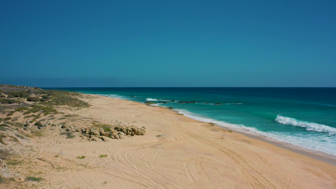 Oblique aerial view of dunes and surf on an empty beach
