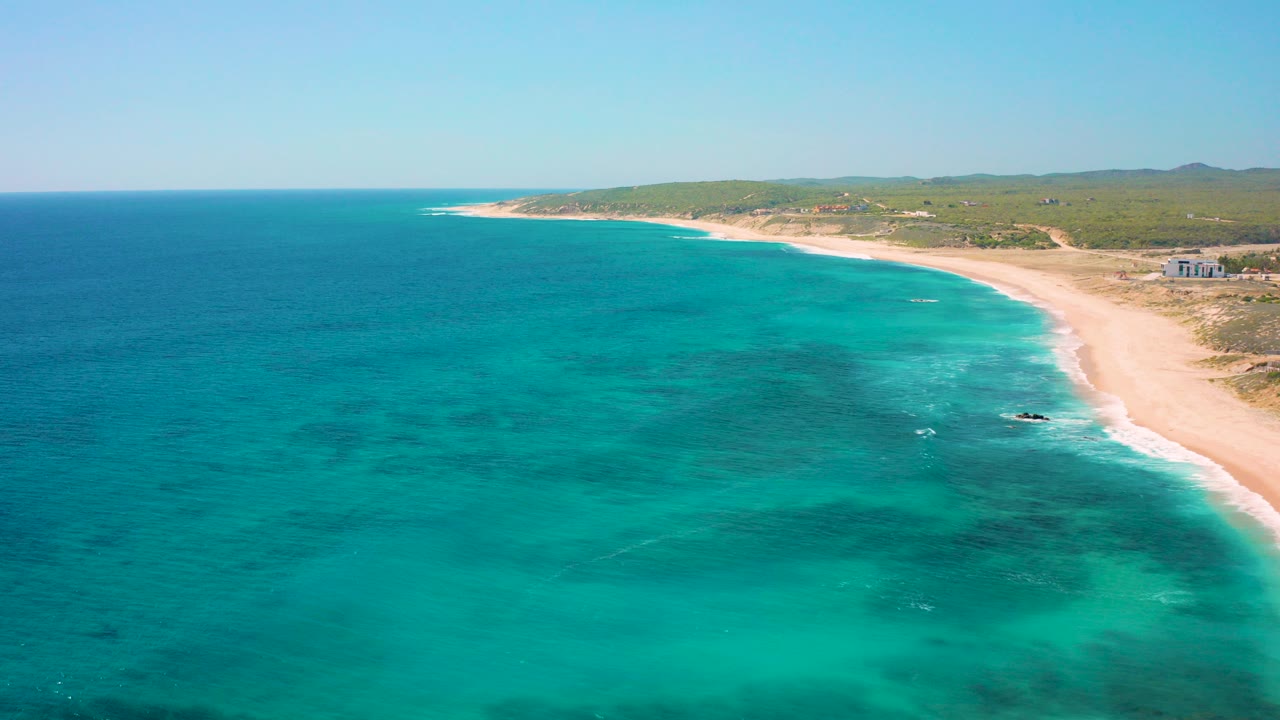 Aerial view of turquoise sea beside a long sandy beach