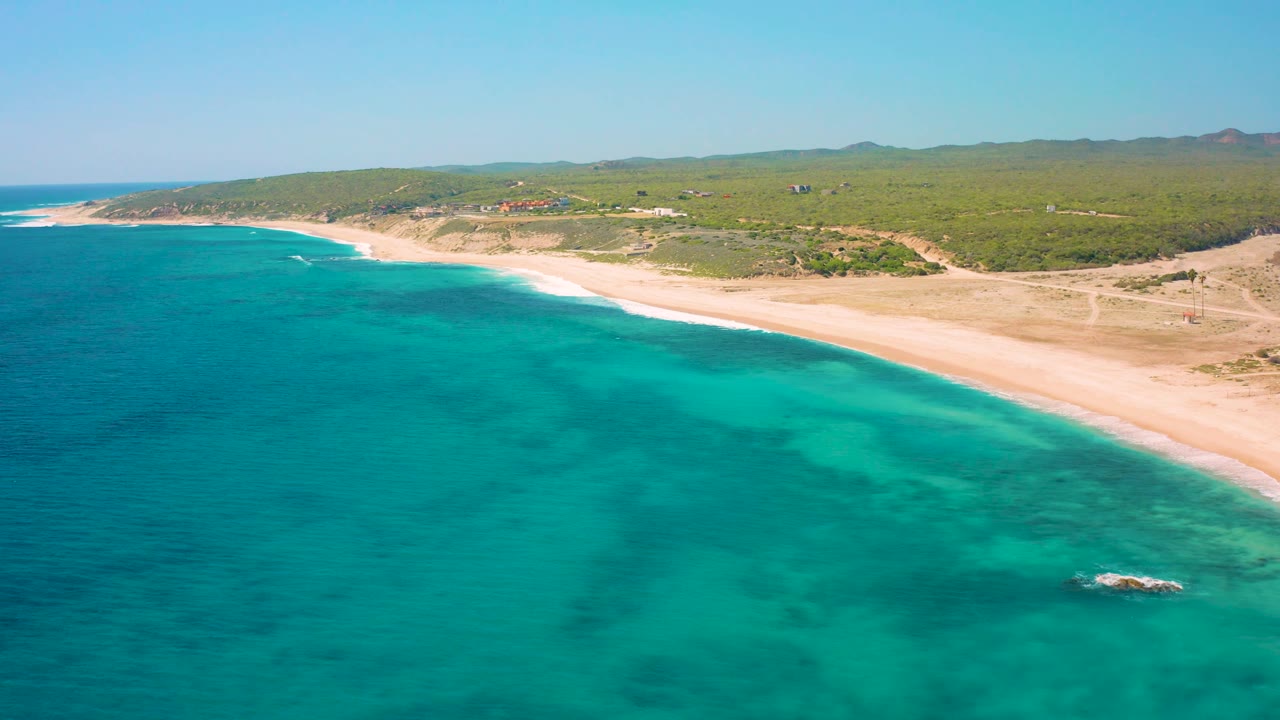 Third frame keeps the El Cardoncito beach running diagonally across the image, with darker patches under the turquoise water, light surf at the sand, green vegetation inland, and no visible people.