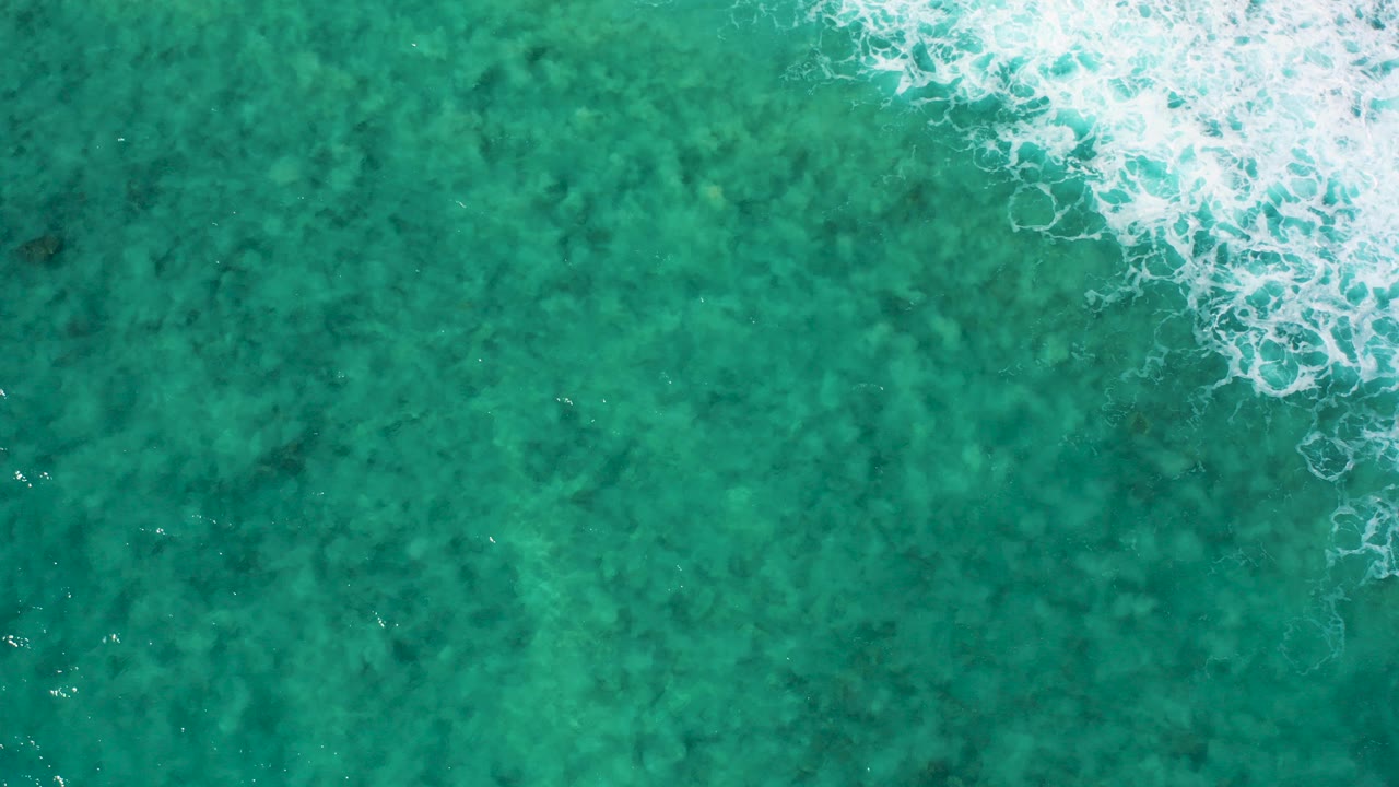 Turquoise ocean water with white foam along the upper right edge.