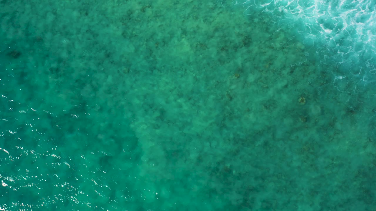 Turquoise sea water at El Cardoncito, Baja California Sur, seen from directly overhead with a soft band of foam near the top and no visible people.