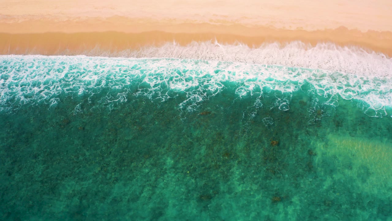 Overhead turquoise surf breaking onto sandy shore