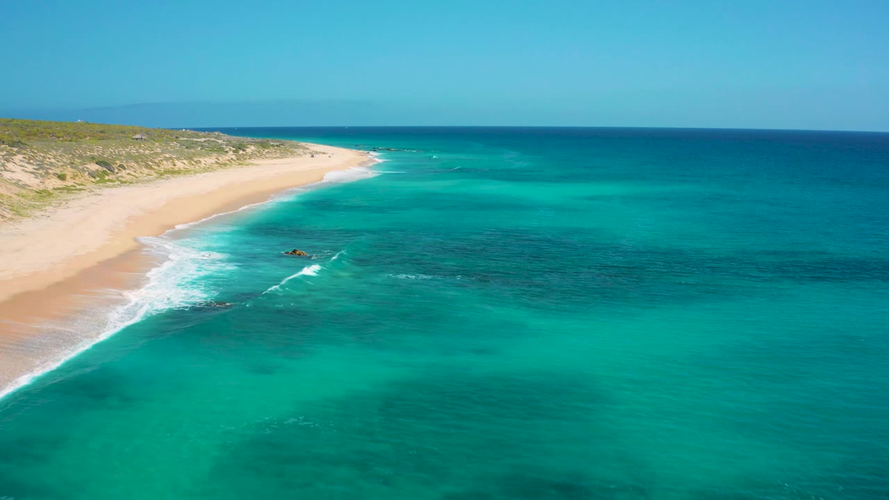 Wide aerial beach scene with waves rolling toward sand