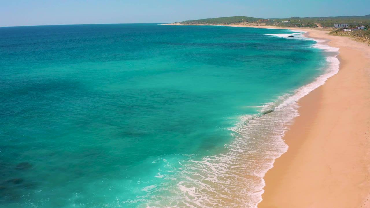 Oblique drone view along a quiet beach and blue ocean