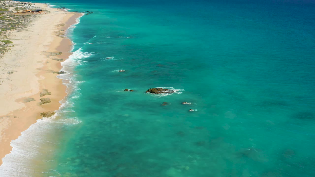Diagonal coastline with foamy waves reaching a sandy beach