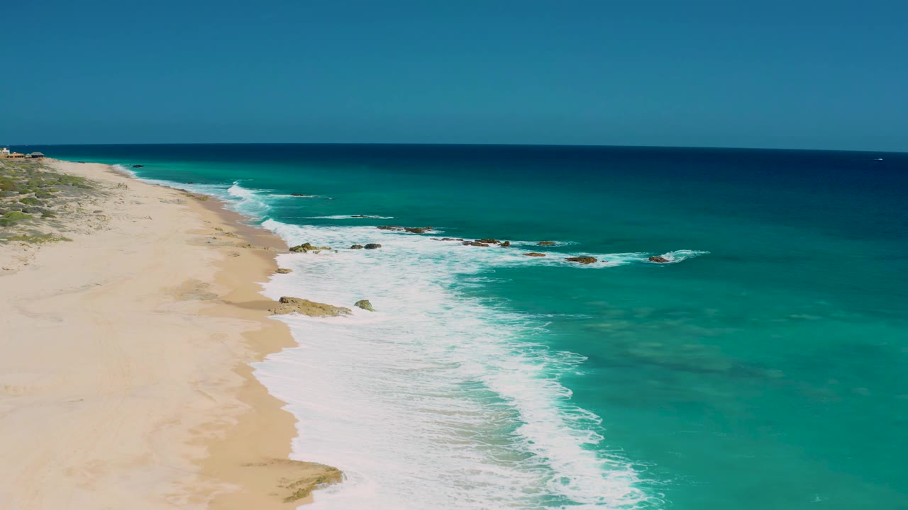Elevated coastline view with waves washing along a sandy shore.