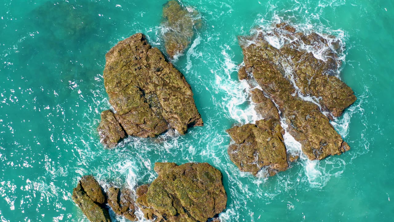 Overhead turquoise water around jagged coastal rocks.