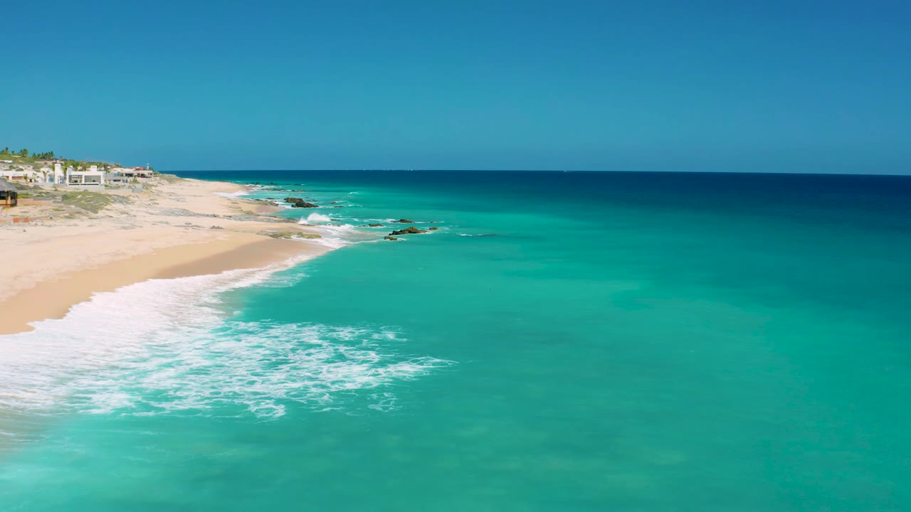 Elevated shoreline view with white foam crossing turquoise water near exposed rocks.