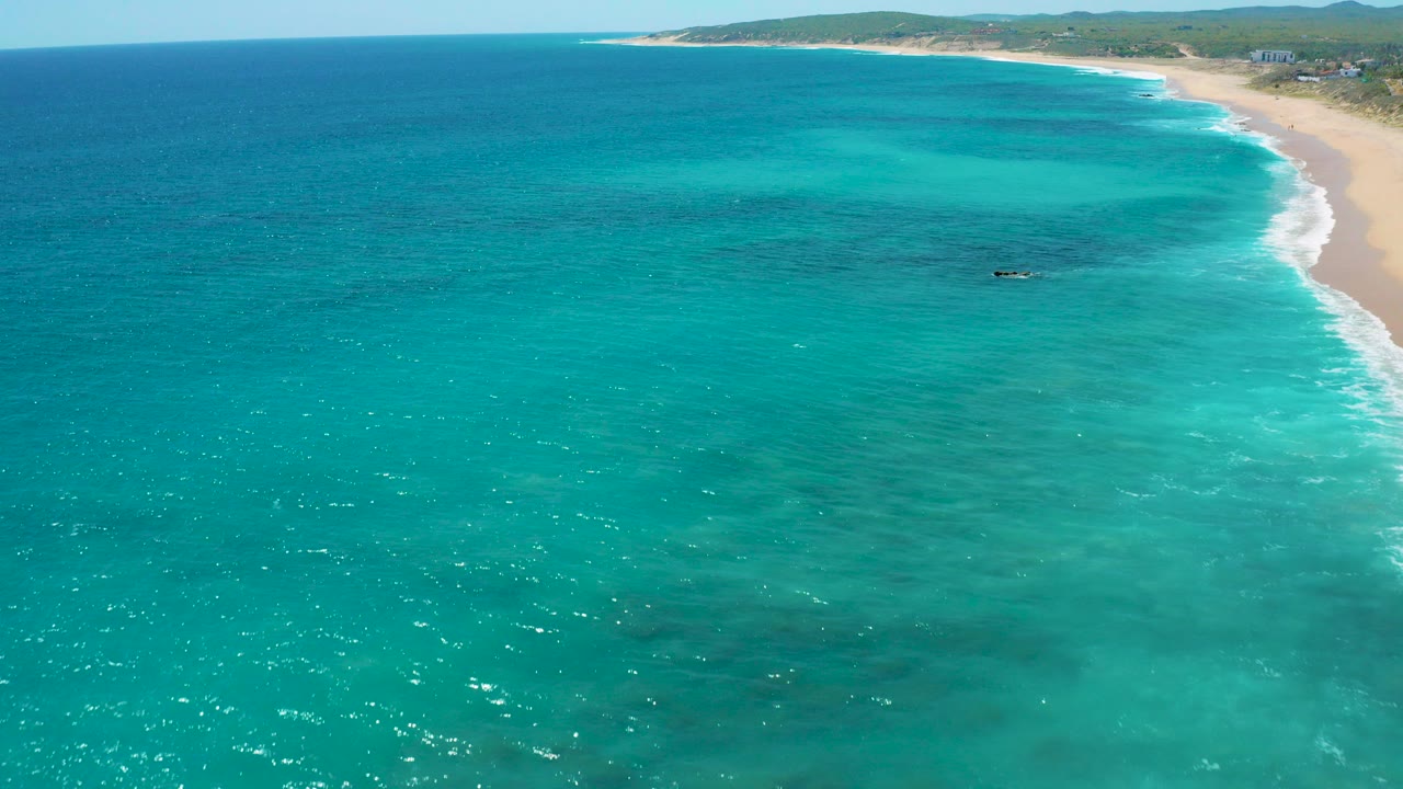 Aerial view of turquoise ocean beside a sandy beach