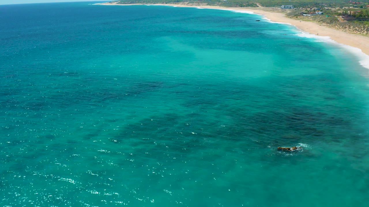Turquoise water with beach and vegetation in the background
