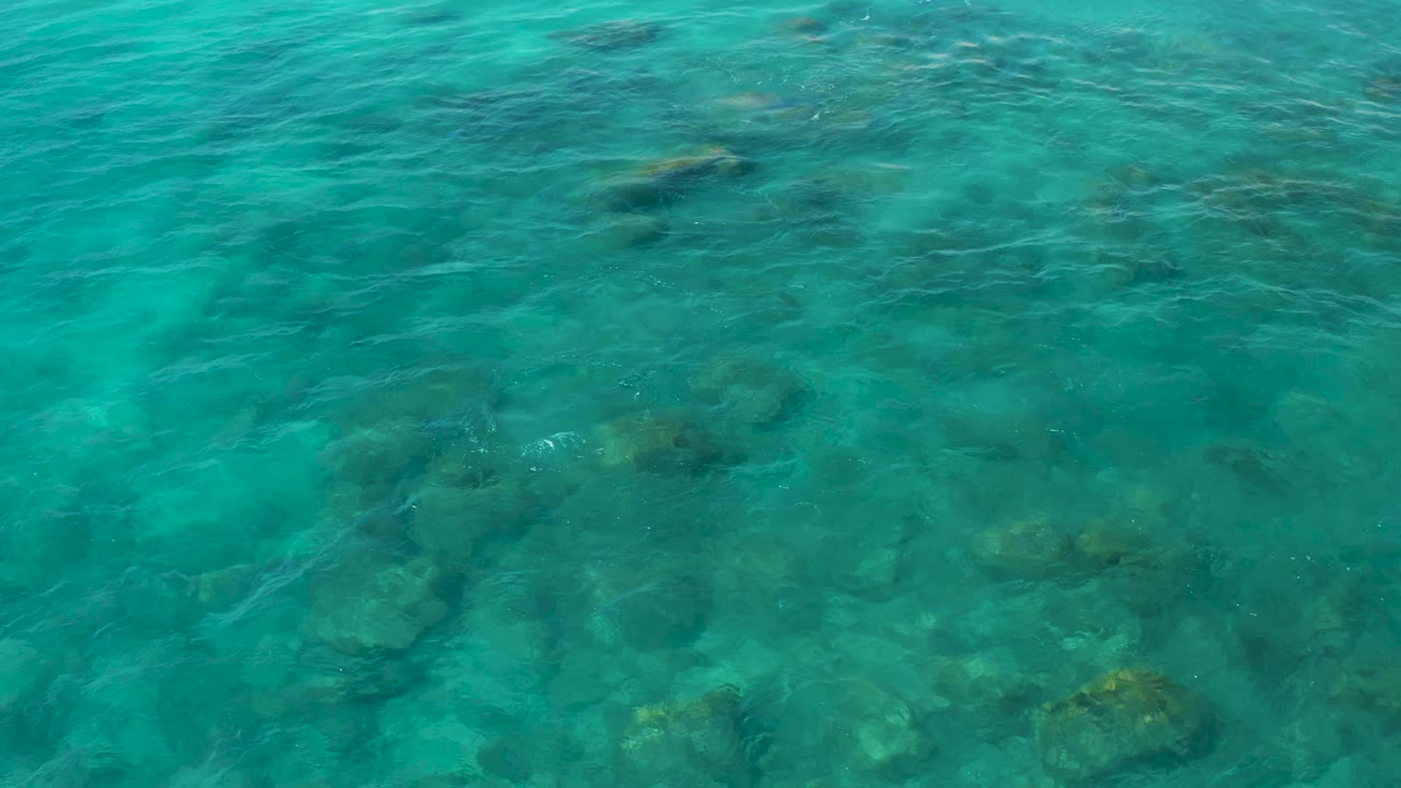 Rippling blue-green water with dark rocks below