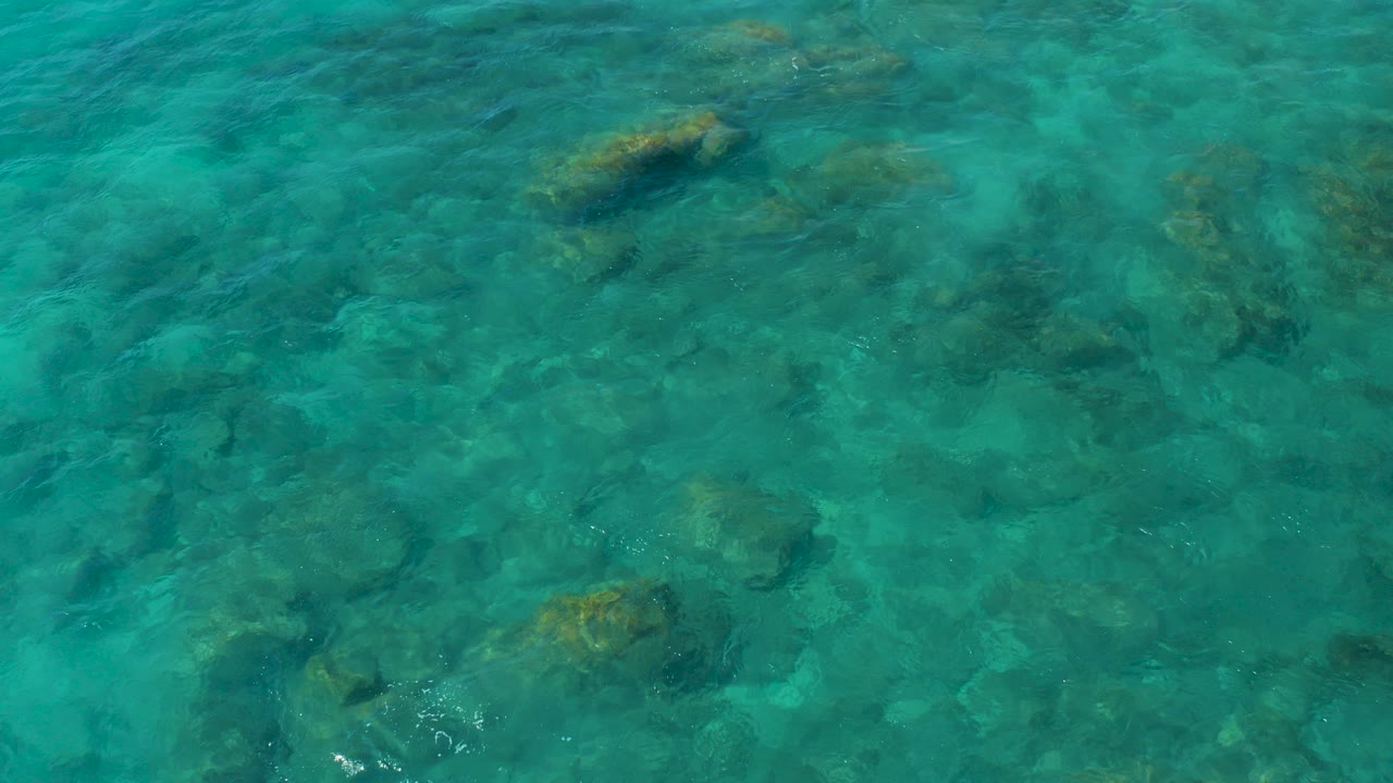 Overhead view of clear turquoise water and submerged rocks at El Cardoncito, Baja California Sur, with no visible people.