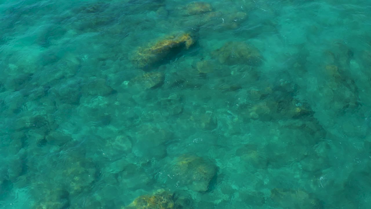 Large submerged rock beneath clear coastal water