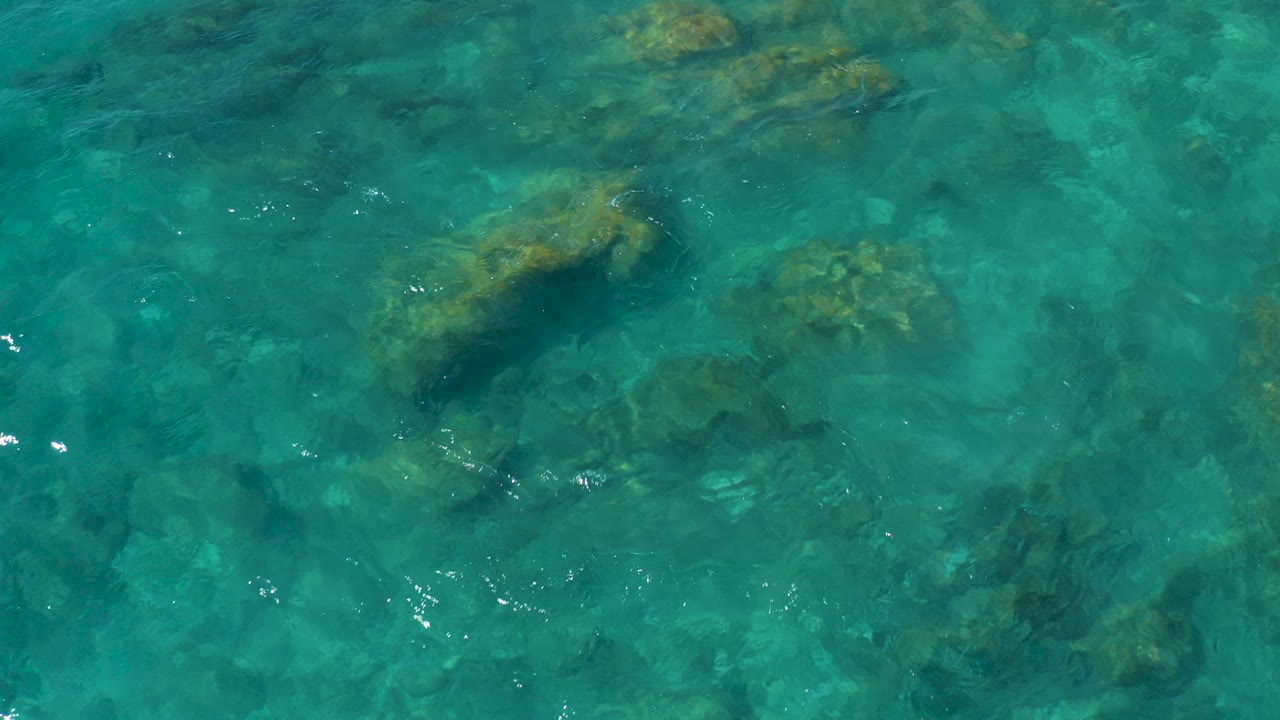 Overhead view of clear turquoise water and submerged rocks at El Cardoncito, Baja California Sur, with no visible people.