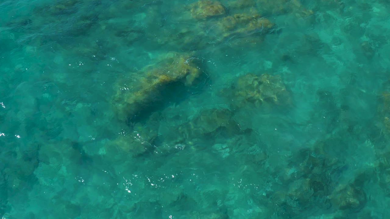 Clear blue water with a large underwater rock