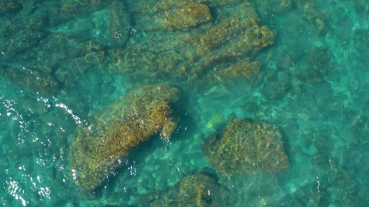 Clear turquoise water over submerged rocks.