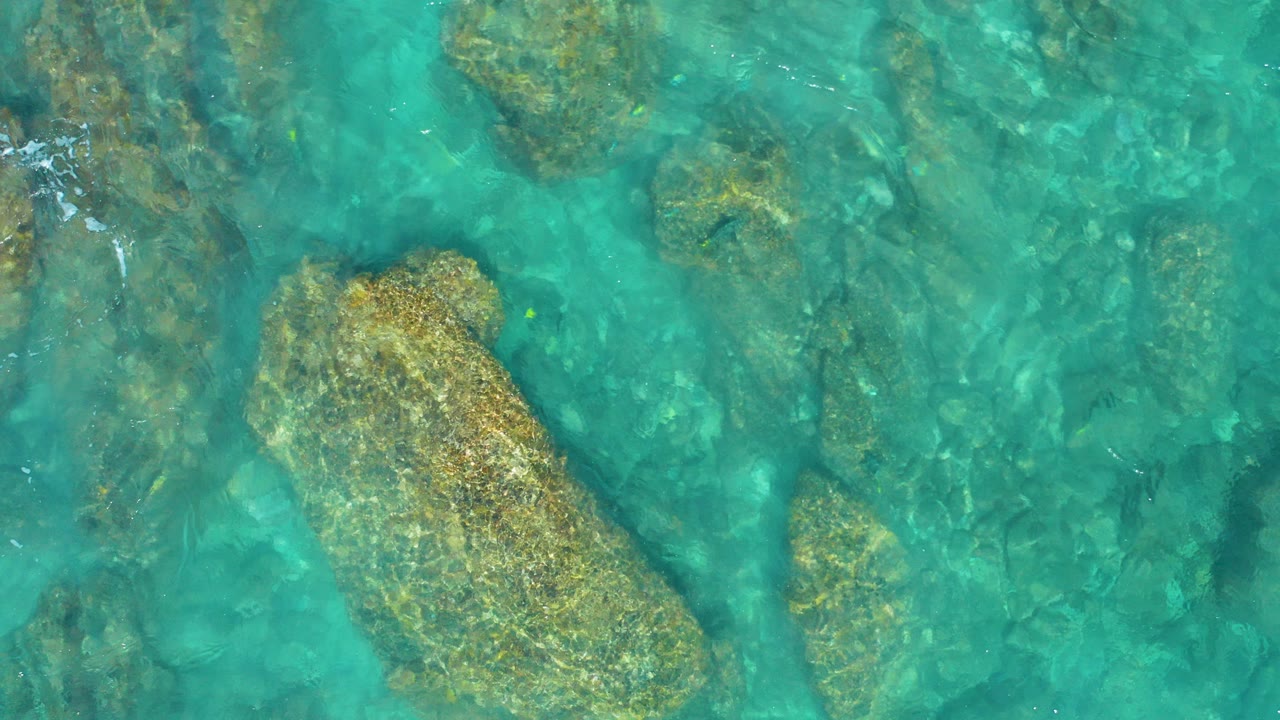 Overhead view of turquoise water covering beige submerged rocks at El Cardoncito, Baja California Sur, with no visible people.